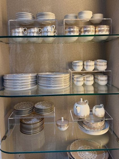 A beautiful crockery set displayed on glass shelves with acrylic risers. This setup creates a clean, gallery-like feel, turning your dinnerware into a design element.