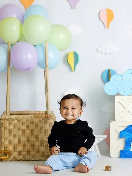 A beautiful portrait taken before the cake smash begins. This little one is all smiles in our popular hot air balloon setup, ready to celebrate his first birthday.