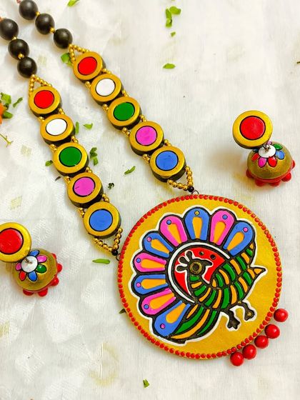 This version of the block-printed peacock set features a yellow circular pendant. The bright background makes the colors of the peacock pop, and it's paired with a simple black bead chain.