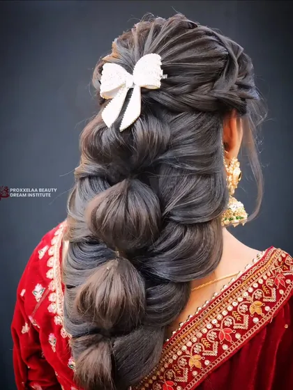 This isn't your average braid. I've created a voluminous bubble braid, adding texture and finishing it with a stylish white bow for a look that's both playful and elegant, ideal for a sangeet or reception.