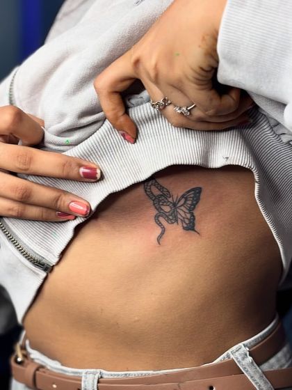 A delicate butterfly and snake tattoo on the rib cage. This design symbolizes the balance between transformation and rebirth.