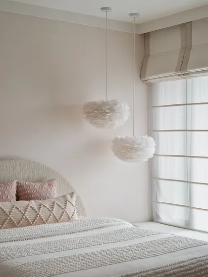 We used soft, feathery pendant lights in this bedroom to add a touch of whimsy and texture. The color palette is kept minimal and muted, creating a serene and dreamy atmosphere.