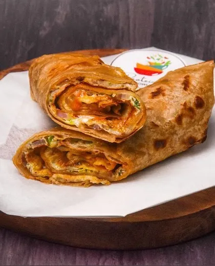 A classic egg roll, cut in half to show the filling, served on a wooden board. The dark background makes this popular street food item look like a gourmet offering.