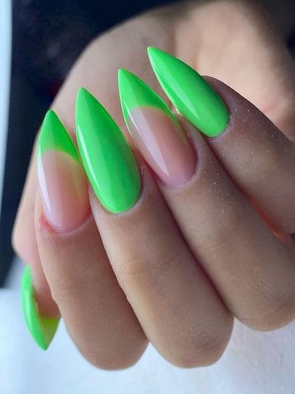 A striking stiletto nail set combining a nude base with vibrant neon green for a bold, graphic French tip effect.