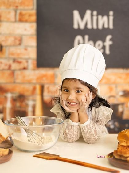 A candid moment of thought from our mini chef. Even when she's not looking at the camera, her personality shines through in this fun kitchen setup.