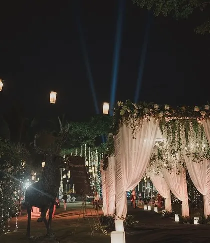As dusk settles, the entrance transforms. Here, hanging lanterns and spotlights create a warm and inviting glow, guiding guests into the evening's festivities.