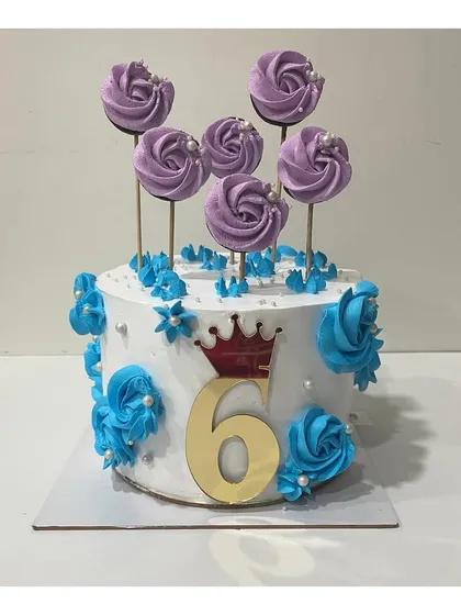 A custom Dutch truffle cake for a 6th birthday, decorated with blue flowers and purple lollipop-style toppers.