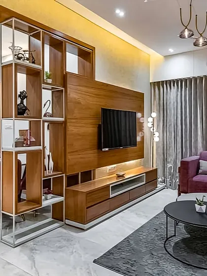 This living room features a custom-designed TV entertainment unit that also functions as a stylish partition. The combination of wood paneling and open shelving creates a focal point while subtly dividing the space without closing it off.