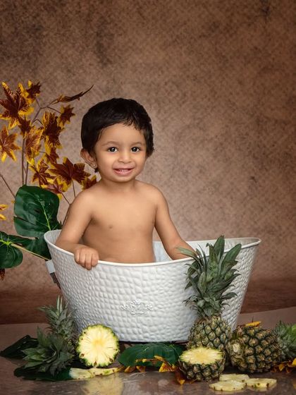 "I'm shoot ready! Let's begin the fun!" A happy boy smiles from his pineapple-themed bath, ready for his close-up.