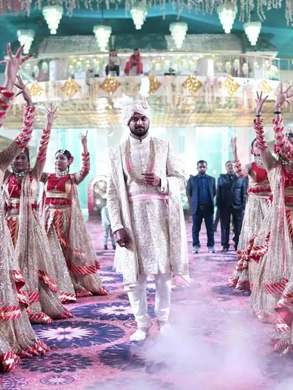 The groom makes his royal entry, walking confidently through a pathway of synchronized dancers. The use of low-lying smoke adds a touch of drama and focuses all attention on his arrival.