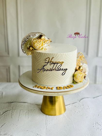 Elegant and timeless, just like their love. A beautiful white and gold anniversary cake for 'Mom & Dad', featuring a delicate texture and floral accents.