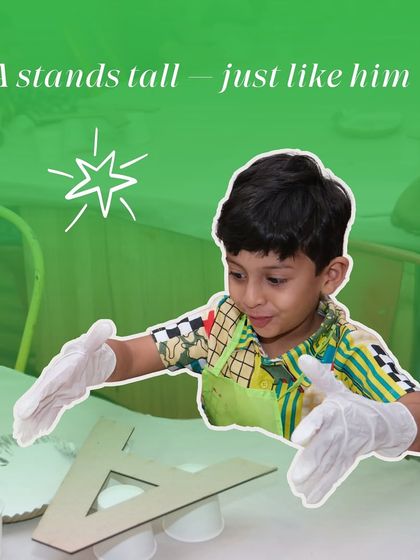 A young boy stands proudly with a large wooden letter 'A' he is about to paint. My workshops help build confidence and a sense of accomplishment.