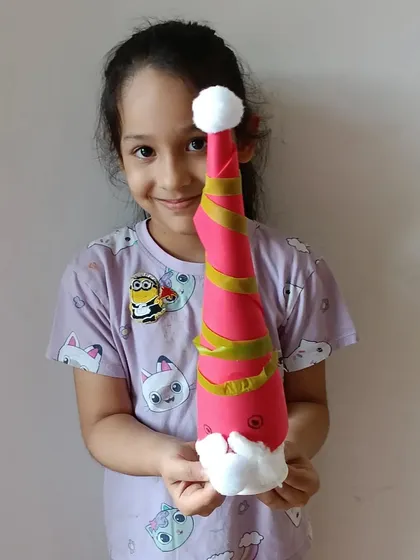 A student holds up the adorable Santa Gnome she made in our winter workshop, crafted from simple, fun materials.