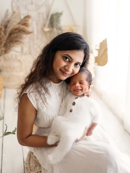 Just look at that dimple! A mother holds her smiling newborn, and his little dimple is the star of the show. So much personality in such a tiny person.