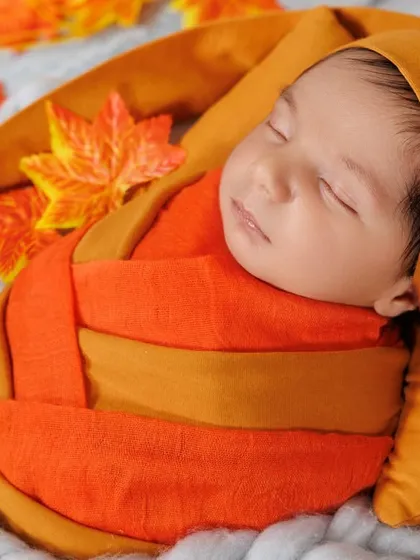 Wrapped snugly in autumn colors, this newborn sleeps peacefully. I use creative swaddling techniques to keep babies comfortable and secure.