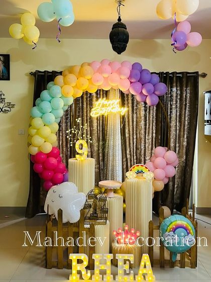 A beautiful rainbow-themed balloon arch in pastel colors. This home setup for a 9th birthday includes cloud and rainbow props for a magical touch.
