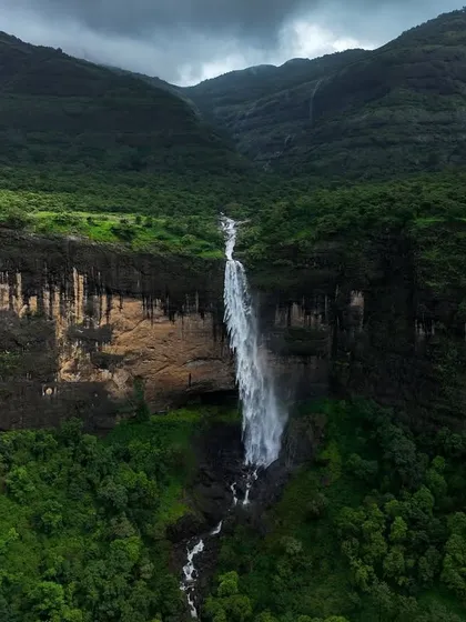 A wide shot of Daityasur Waterfall, showing its place within the larger valley. This perspective helps to tell the story of the landscape and the power of the water that shapes it.