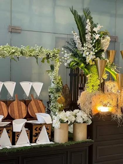 An artfully arranged station featuring natural wood elements, lush floral arrangements, and decorative pieces. This setup showcases our ability to integrate food service with high-end event decor seamlessly.