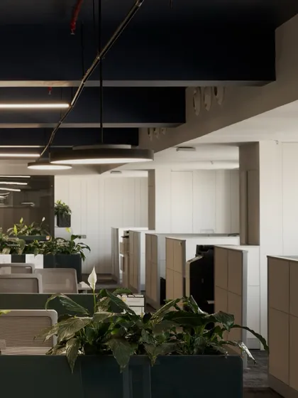 Another perspective of the workstation layout, showing the clean lines of the cubicles and the dark, exposed ceiling with modern light fixtures. This industrial-chic element adds character to the space.