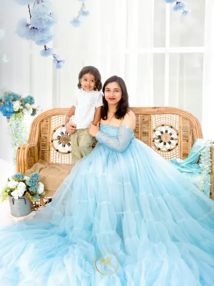 A mother in a flowing blue gown sits with her young son, a beautiful portrait that can also be part of a maternity session for a second child.