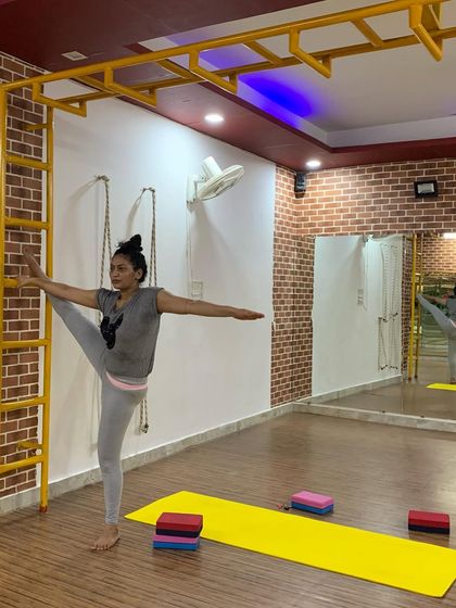 Using the wall bars to work on a side split (Utthita Hasta Padangusthasana variation). This provides stability while the student focuses on opening the hips.
