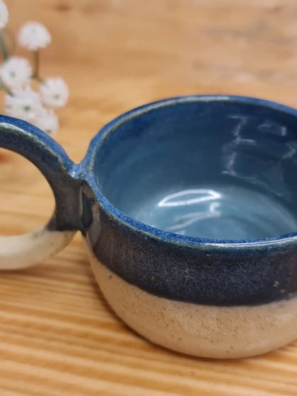 This cup-shaped tealight holder will make a super cozy addition to any room. The large handle and stunning blue glaze make it a unique decorative piece.