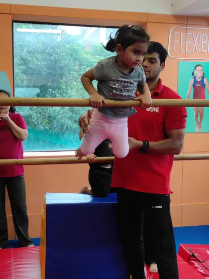 A coach provides gentle support as a young child learns to navigate the parallel bars. This one-on-one attention helps build trust and confidence.
