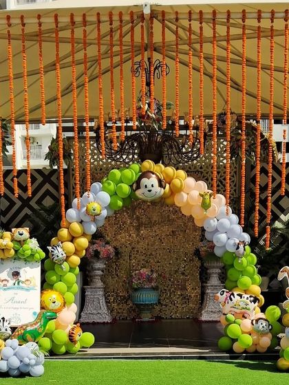 Combining traditional elements with a fun theme. For this outdoor Mundan ceremony entrance, I created a balloon arch with jungle animals and paired it with beautiful hanging garlands of marigold flowers for a festive, welcoming touch.