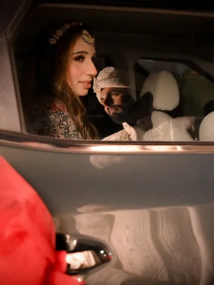 A tender moment shared between the newly married couple in the car after the ceremony. This candid photograph captures the beginning of their journey together, away from the crowds.