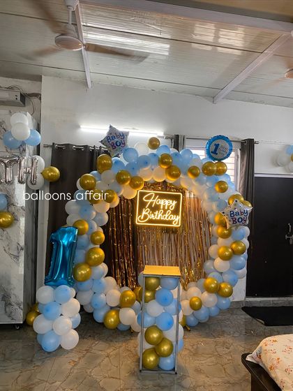 A wider shot of the blue, white, and gold first birthday decoration in a home setting.