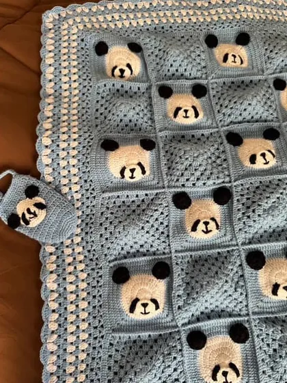 A close-up of the panda blanket, showing the neat stitch work and a tiny matching panda accessory.