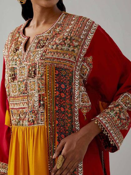 A close-up of a red and yellow ensemble, showcasing the incredibly detailed and colorful patchwork embroidery that defines this artistic piece.