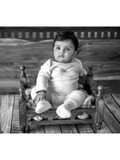 A beautiful black and white portrait of baby Anika on the miniature bed. The contrast and composition create a simple yet powerful image of the six-month-old twin.