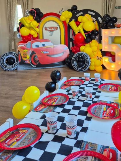 A vibrant Disney Cars party for a 5th birthday. The setup includes a large Lightning McQueen prop, a light-up number "5", and a fully themed table setting.