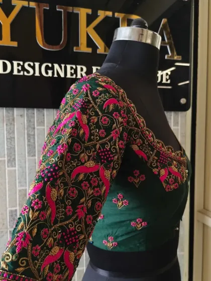 A front-side view of the emerald green blouse, highlighting the detailed embroidery on the sleeve and the elegant neckline.