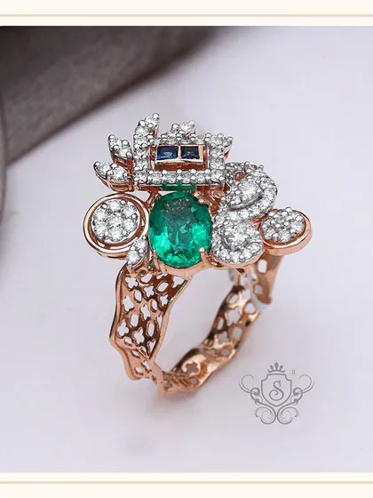 An avant-garde design for the bold and fashionable. This custom ring features a central oval green gemstone, surrounded by an abstract arrangement of diamonds and sapphires on a textured rose gold band.