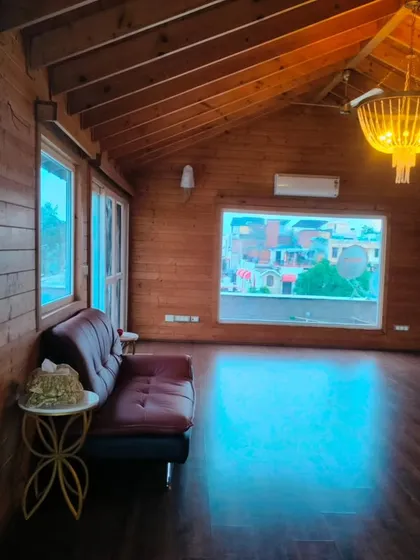 The interior of a rustic wooden cottage we built on a terrace in New Friends Colony. This shows the quality of our interior finishing, with wood-paneled walls and ceiling, creating a warm and cozy retreat.