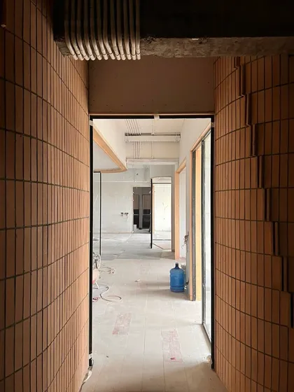 A corridor lined with vertically laid bricks, creating a unique textured effect. This view from a work-in-progress site shows how we use common materials in unconventional ways.