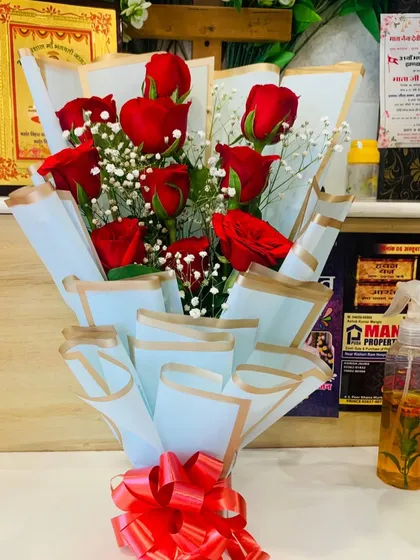 A simple bouquet of red roses and baby's breath wrapped in light blue paper. This is a great example of a classic, affordable, and beautiful floral gift.