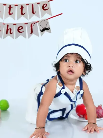 A baby chef crawls across the kitchen floor, ready to cook up some fun. The simple white background keeps the focus on the adorable subject and his props.