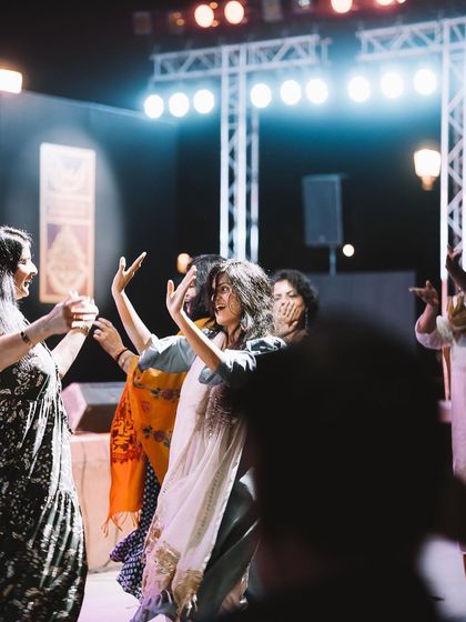 A group of friends dancing together under the bright stage lights of a concert. This photo is all about the shared experience and collective energy of a live performance.