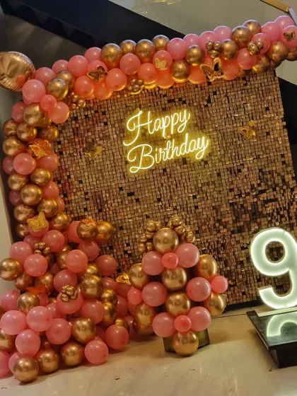 A beautiful rose gold theme for a 9th birthday, featuring a sequin wall, a balloon arch, and a light-up number.
