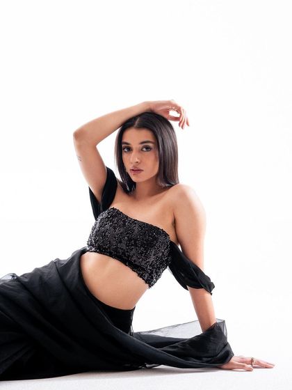 A seated portrait that showcases the sparkling detail of the sequin blouse. The model's direct gaze and relaxed pose create an intimate and confident image.