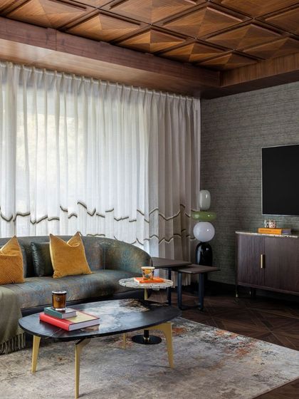 This family lounge features a coffered wood ceiling and textured wallpaper, creating a cozy and intimate atmosphere. The design is perfect for media viewing and casual gatherings.