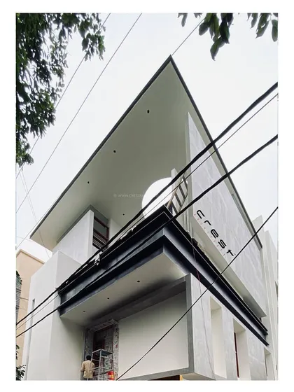 'Residence 96' under construction. This worm's-eye view highlights the building's sharp, angular roofline and minimalist concrete forms against the sky.