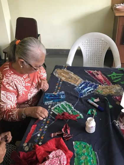 A mentor works on a beautiful upcycled textile art project. We inspire kids to see old fabrics not as waste, but as a canvas for creativity and a resource for making something new.