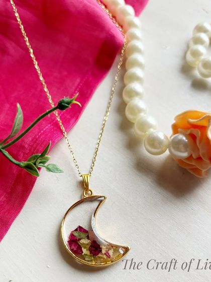 A crescent moon pendant filled with preserved varmala petals. This is a popular and stylish design that turns wedding memories into a fashionable accessory.