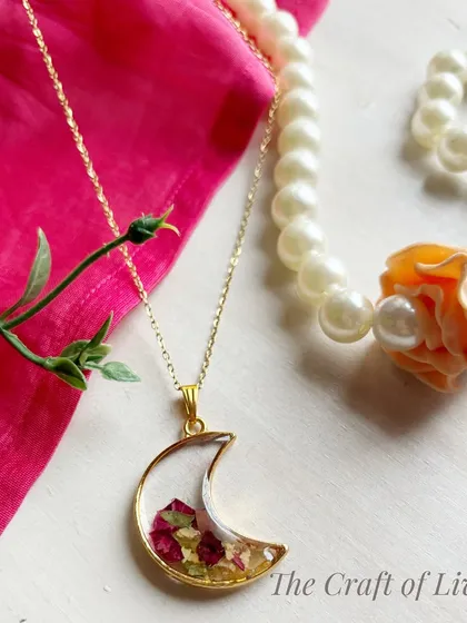 A crescent moon pendant filled with preserved varmala petals. This is a popular and stylish design that turns wedding memories into a fashionable accessory.