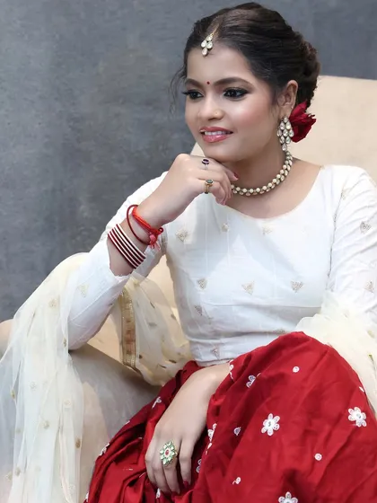 A soft and romantic look for a pre-wedding event, featuring a red rose in the hair and minimal jewelry.
