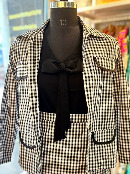 A closer look at the details of my checkered blazer set. The design features classic tailoring with contrasting black trim on the pockets and a matching bow-tie shirt, embodying a chic and professional aesthetic.